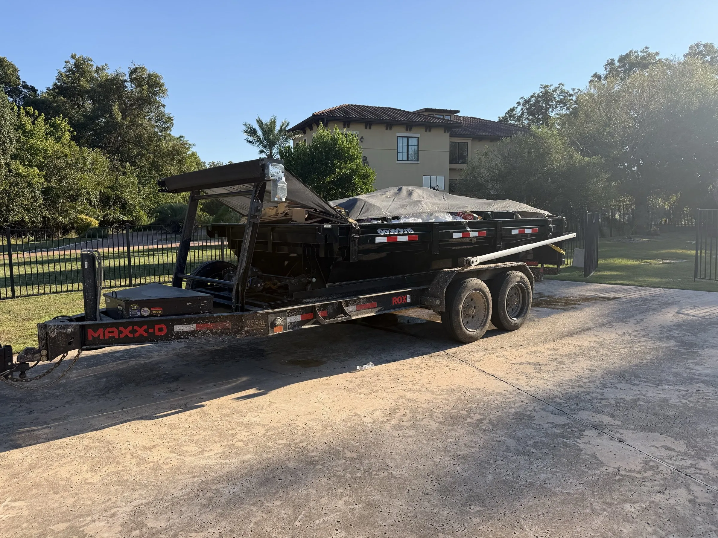 Truck and trailer hauling away a covered, loaded dumpster